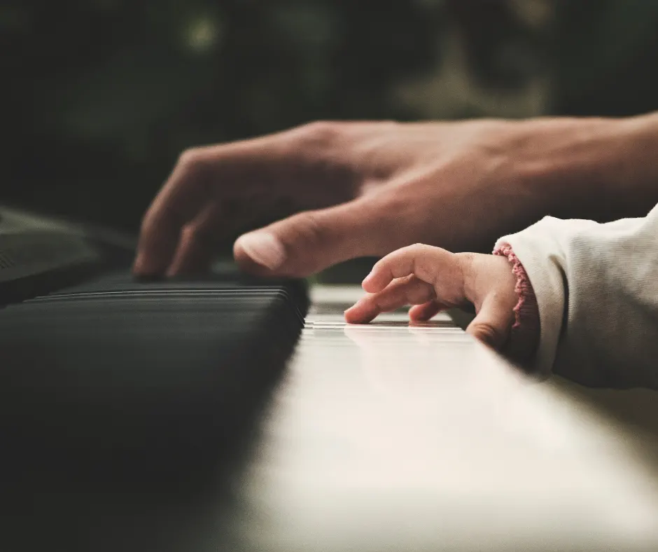 Mano adulta e di bambino che suonano il pianoforte